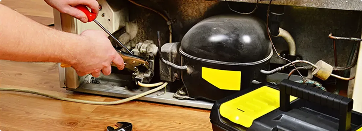 Refrigerator repair technician fixing the compressor and wiring in El Mirage, AZ