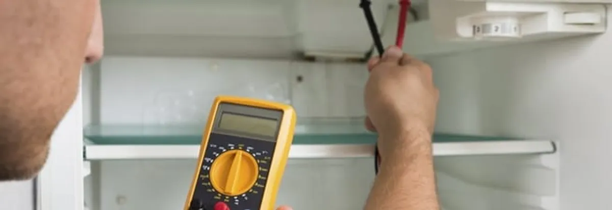 Refrigerator repair technician testing electrical components with a multimeter in Glendale, AZ